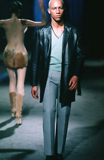 a man in a suit is walking on a runway