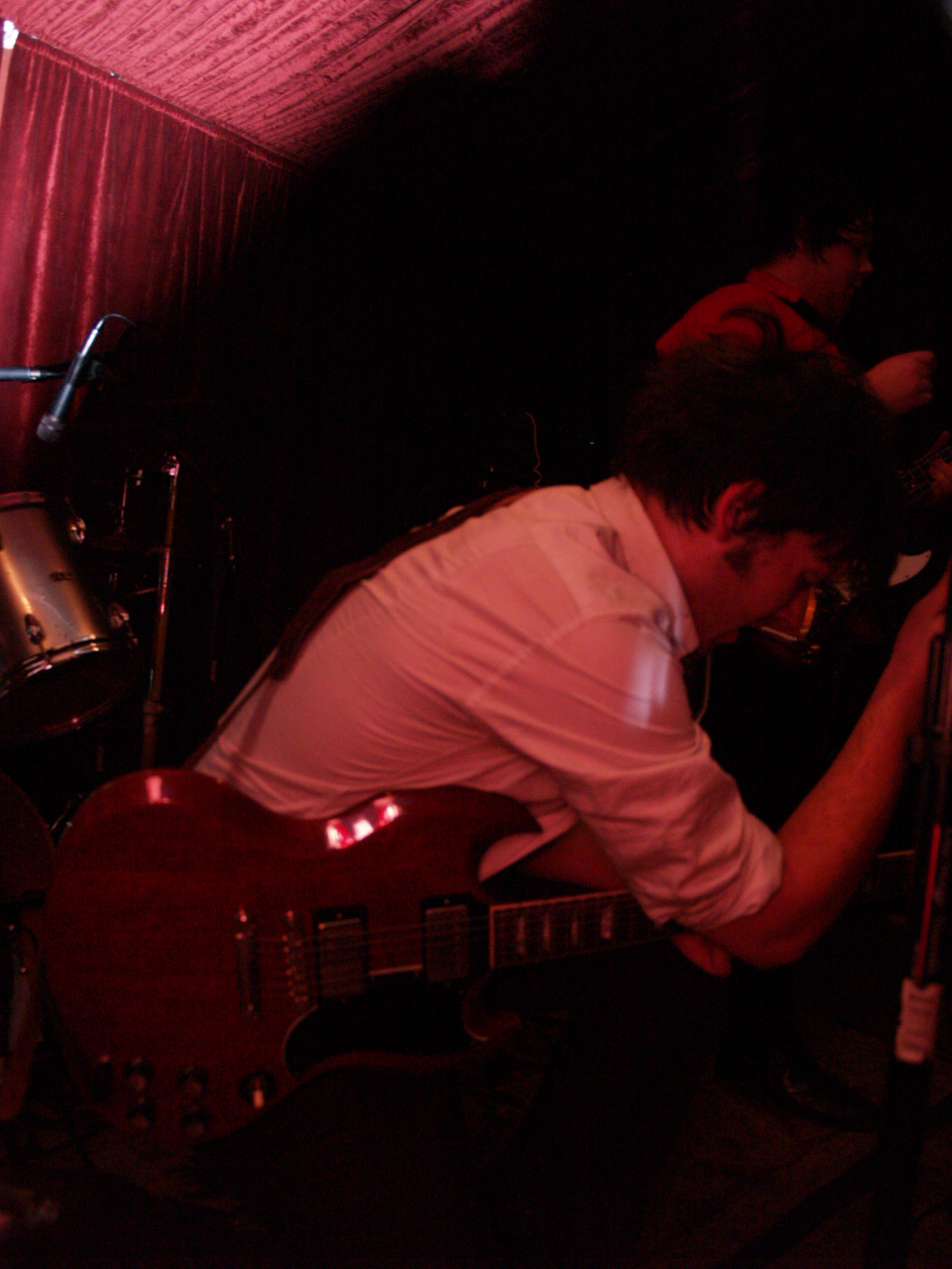 a man playing a red guitar in a dark room