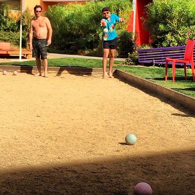 two people in a dirt field with balls on the ground