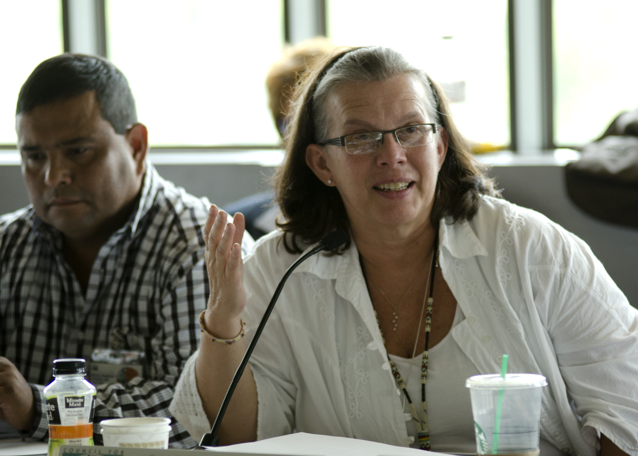 a woman with her hands together talking into a microphone