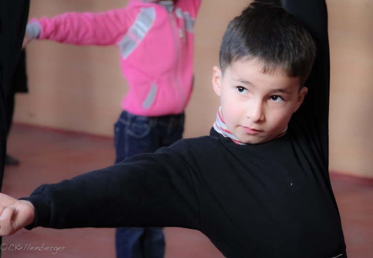 two little boys standing in front of a wall and one boy holding the arms behind his head