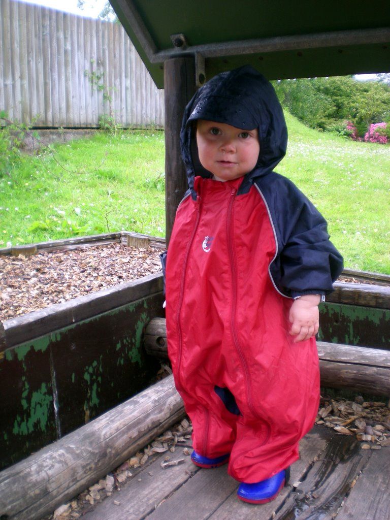 a  in a raincoat standing on a porch