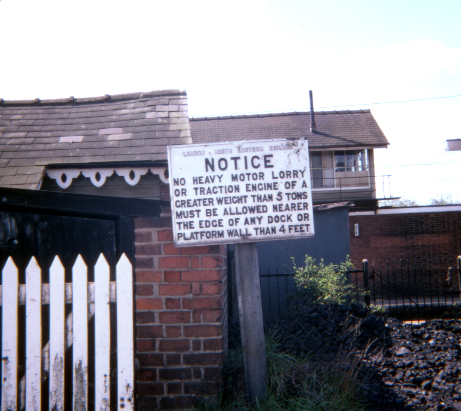 a white sign in front of a red brick building