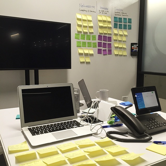 a desk with two computer screens, keyboard, and a phone