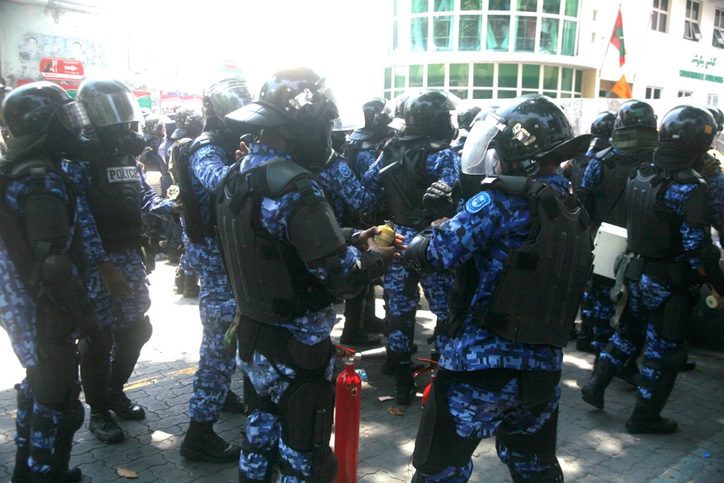 several riot police wearing blue uniforms, all with gas masks