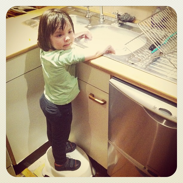 a young child is trying to reach into a sink