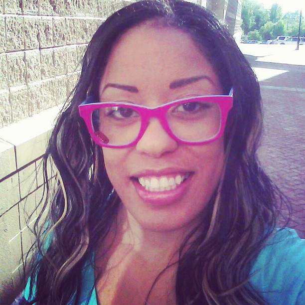 a girl with a blue shirt and pink glasses posing for the camera