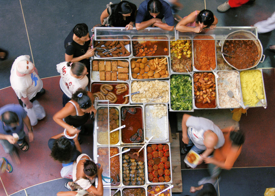 overhead view of many people standing near buffet of food