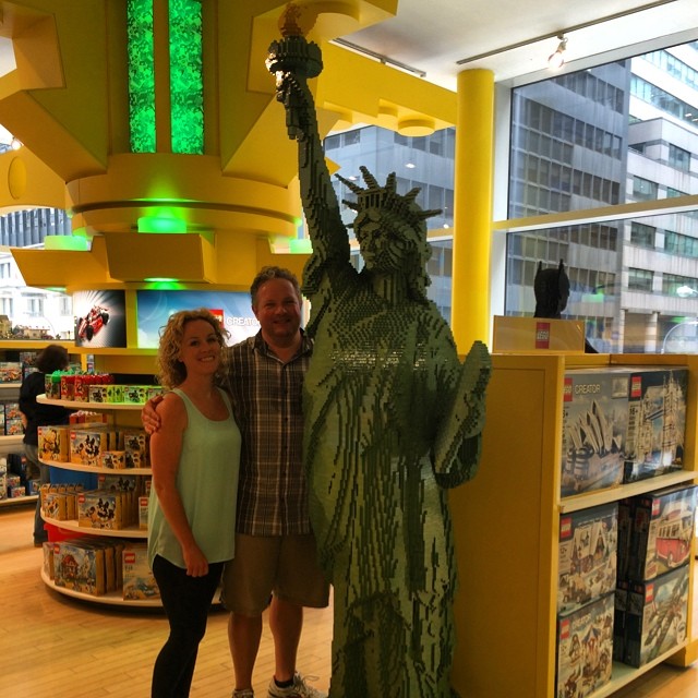 two people standing next to a statue of liberty