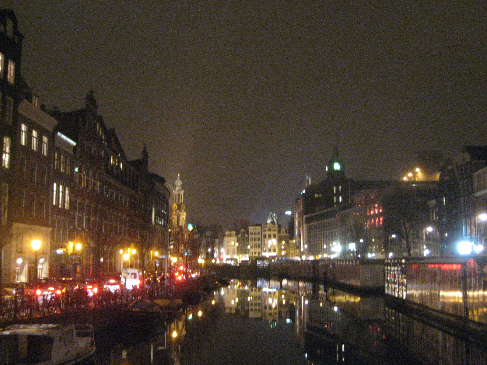 a city scene with lots of boats in the canal at night