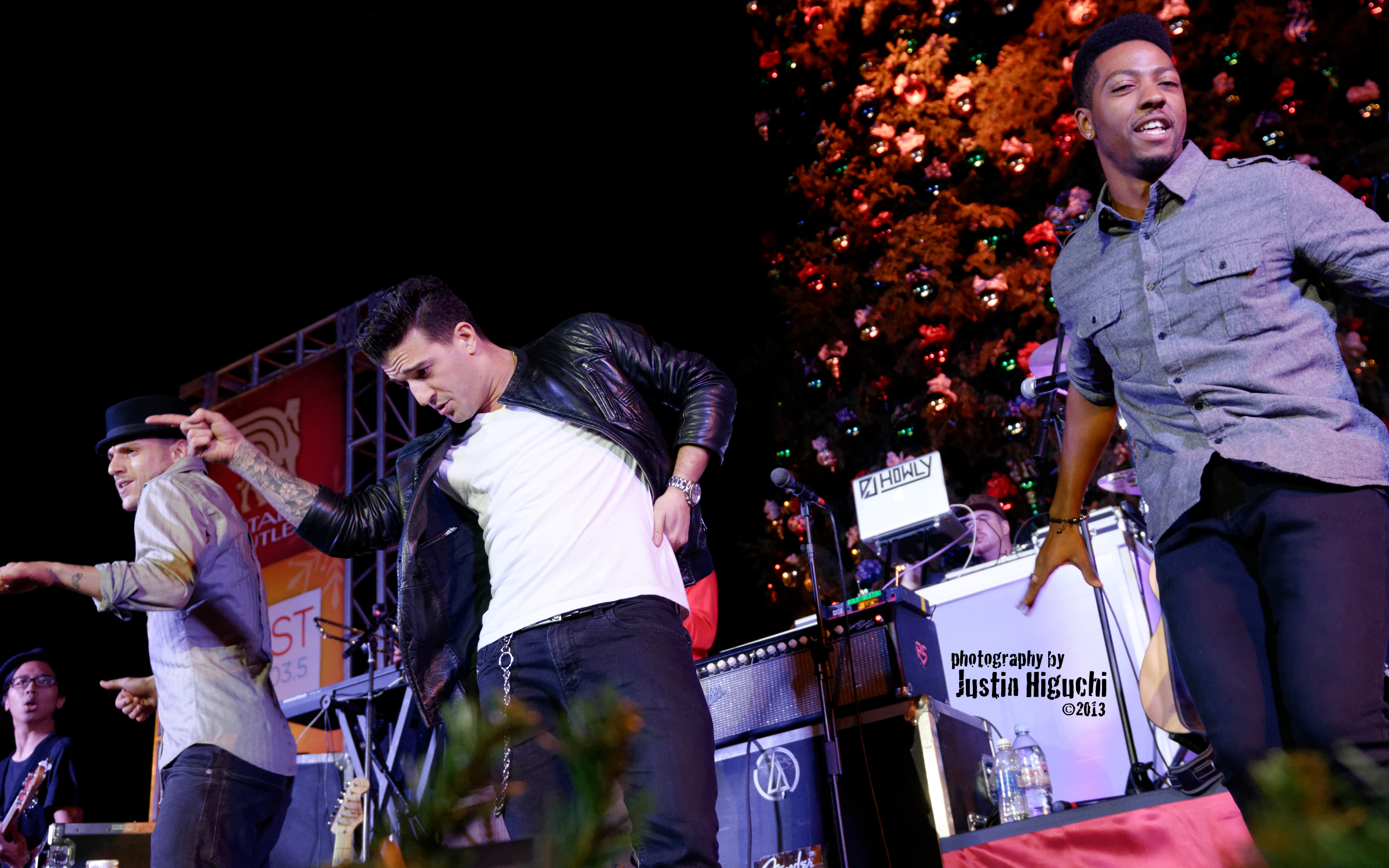 three people dance and smile in front of the crowd