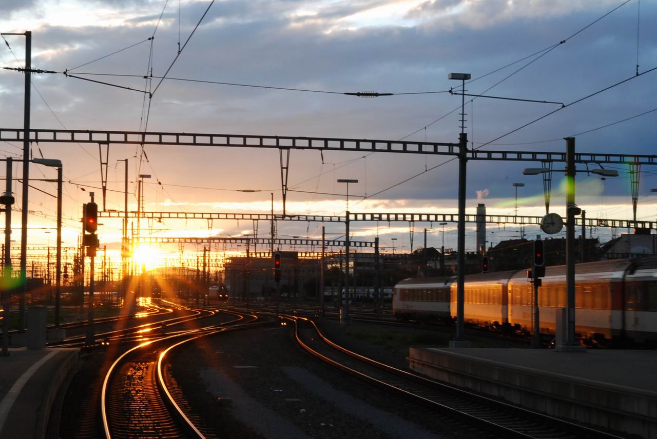 sunset over railway tracks with passing train