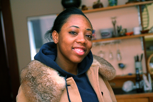 a woman in a brown jacket looks at the camera
