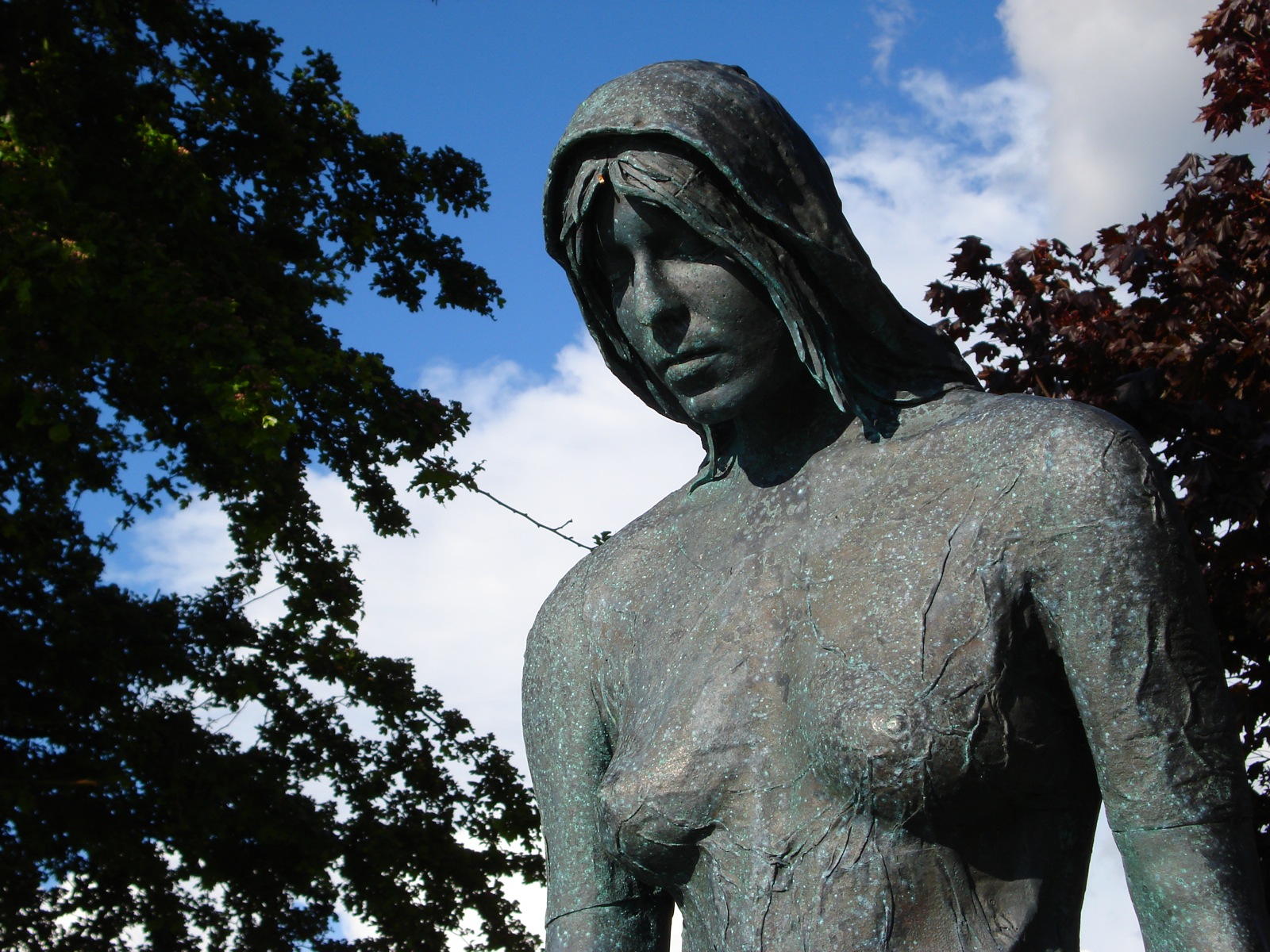 the body of a woman is cast in bronze, with some trees behind