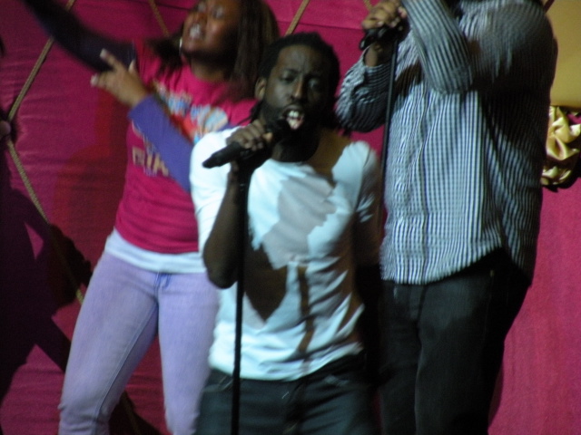 three people stand in front of two microphones