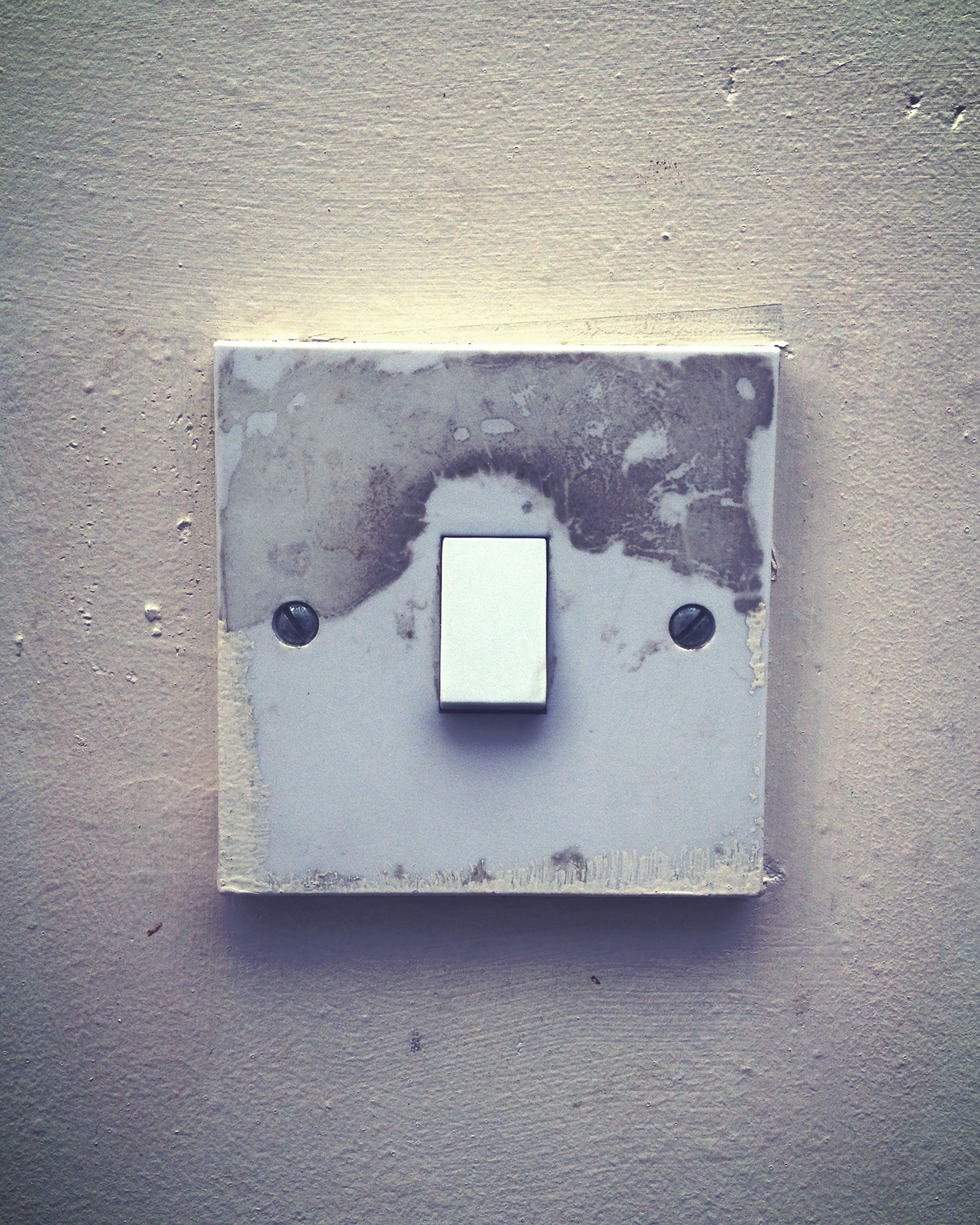 a square light switch mounted to a gray wall