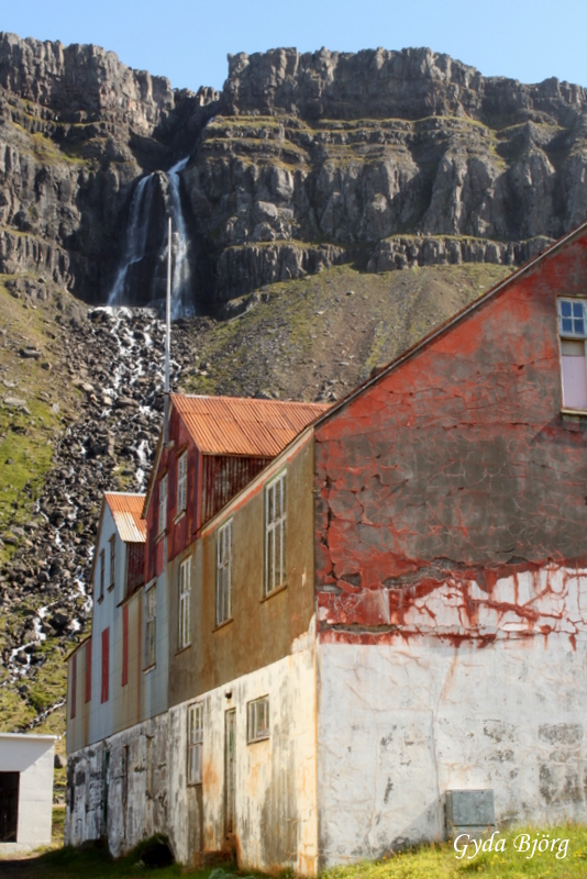 a building sitting next to a lush green hillside