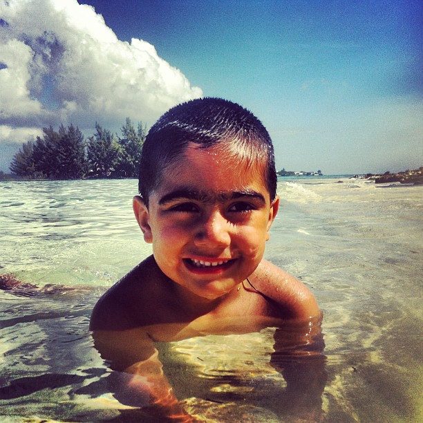 a boy smiles as he wades in the water