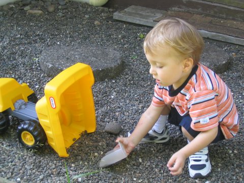 a child playing with a toy tractor next to the road