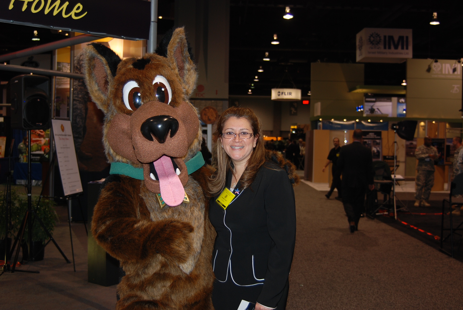 a woman stands in front of a mascot posing for a po