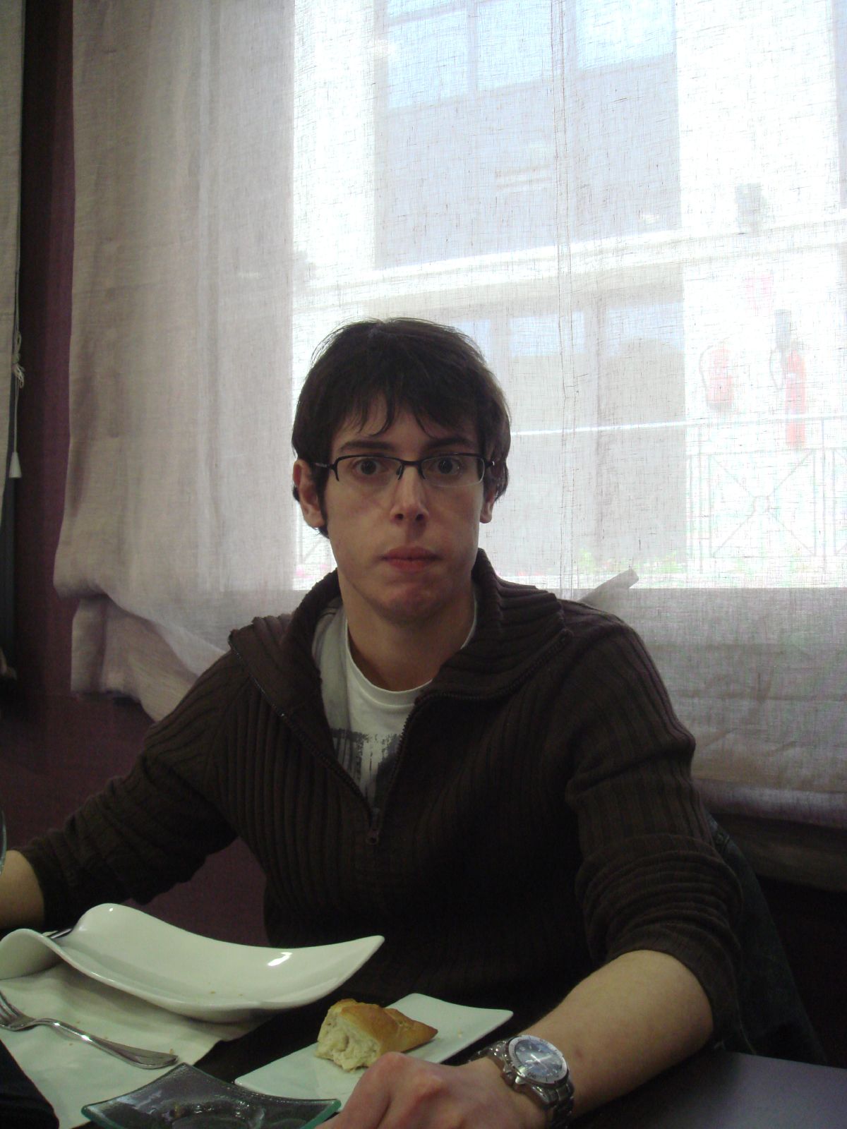 a man sitting at a table with plates and glasses