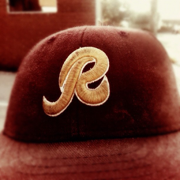 a brown hat with an odd, stylized letter