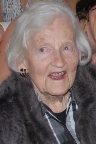 an older woman with white hair wearing a fur vest and smiling at the camera