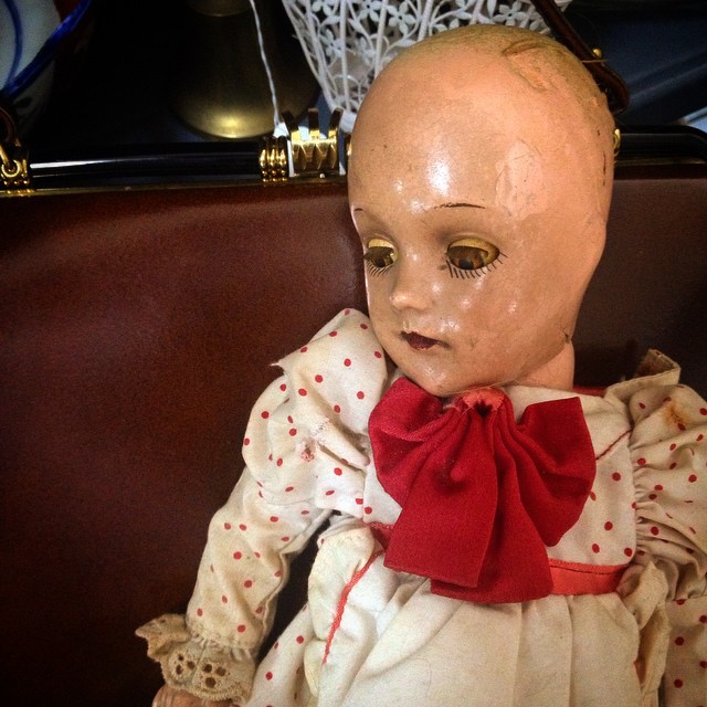 an antique doll has a red bow around its neck