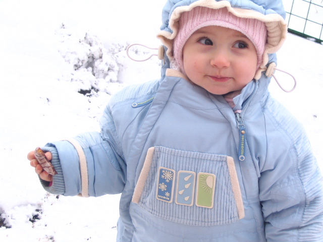 a young child standing in the snow wearing a blue jacket and hat