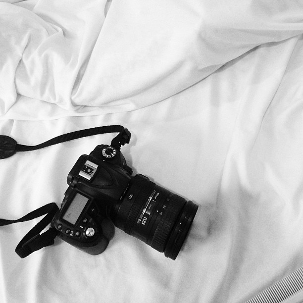 a camera sitting on a bed with white sheets