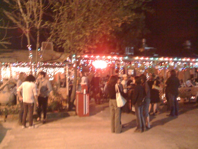a crowd of people standing around a tree decorated with lights