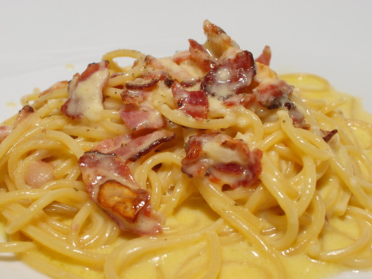 pasta with bacon and sauce on top of a plate