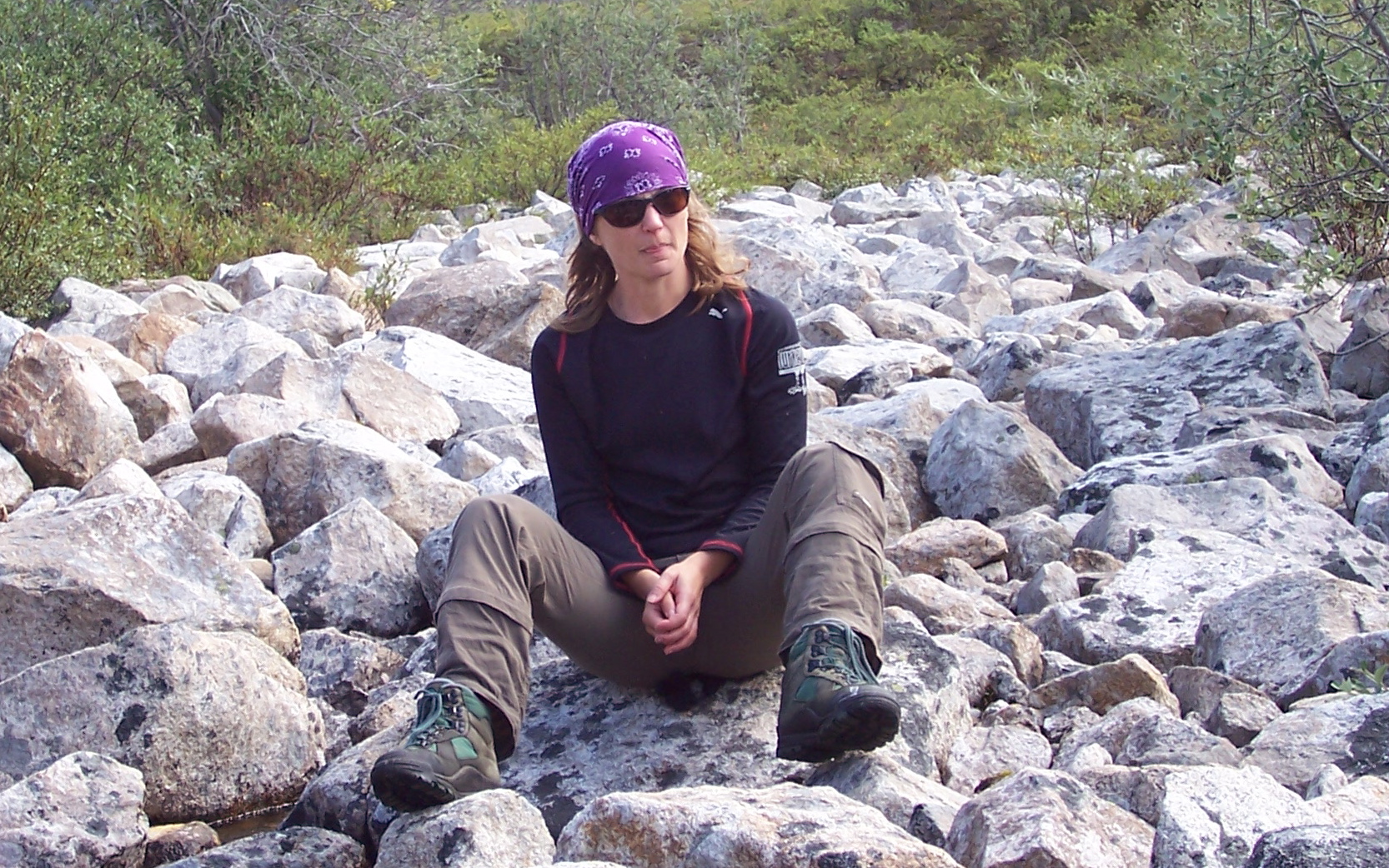 a woman sitting on rocks near water