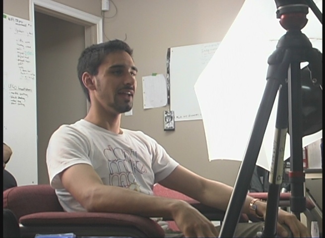 man sitting on a chair in front of camera using a laptop
