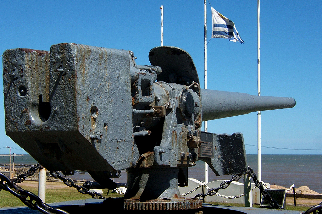 old cannon near some flags and other building