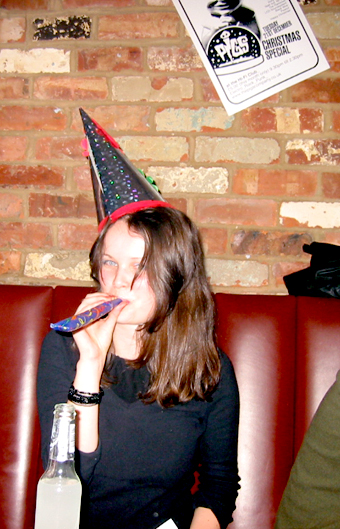 woman in party hat sitting in front of brick wall