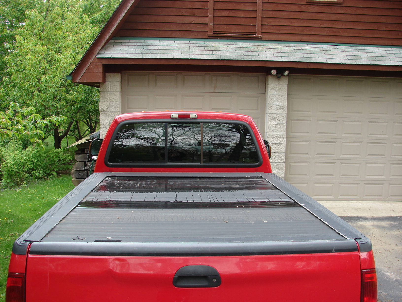 an pick - up truck with an opened flatbed parked next to a garage