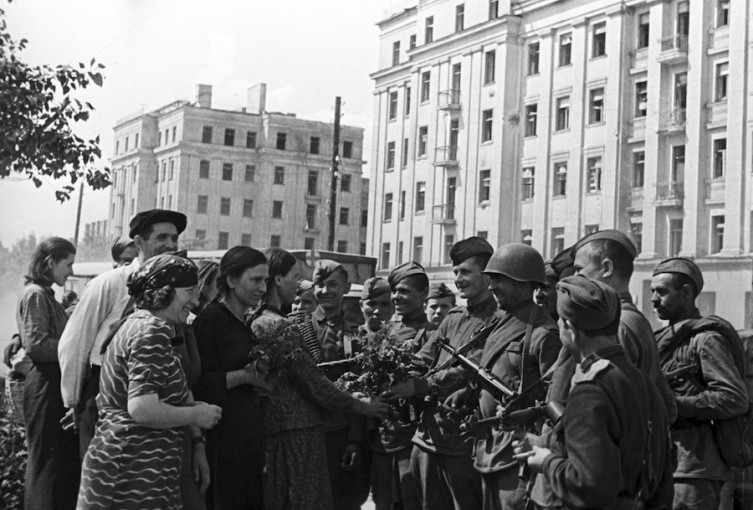 a line of people stand in front of a line of armed soldiers