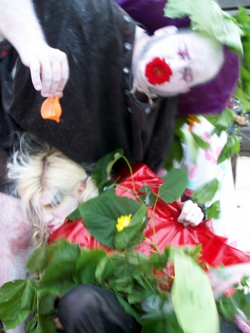 the clown is holding a red ribbon near the flowers