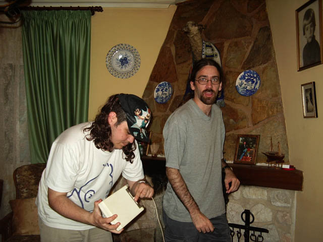 two men in a living room with plates hanging above them