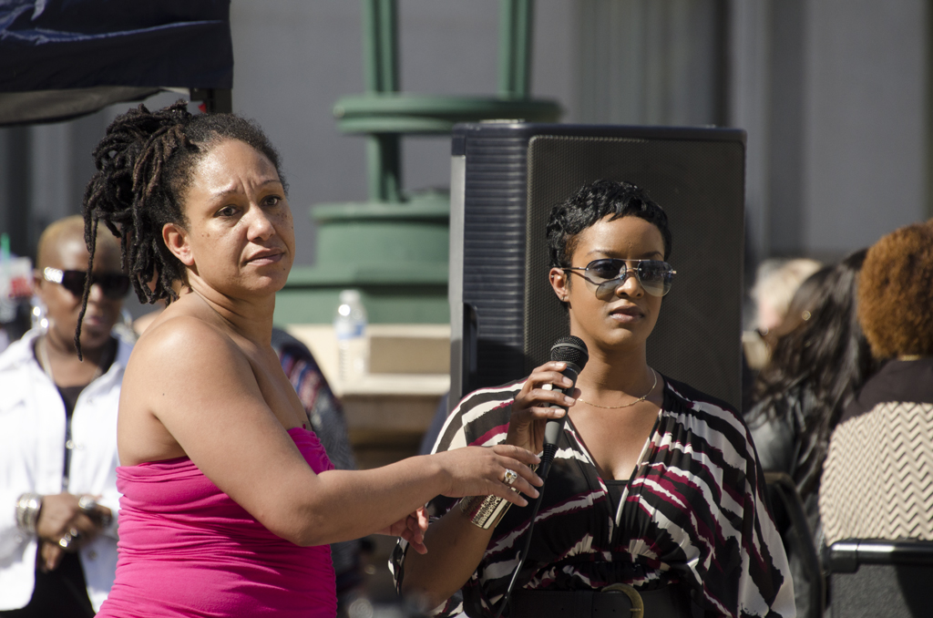 a woman is talking on a microphone while another holds soing