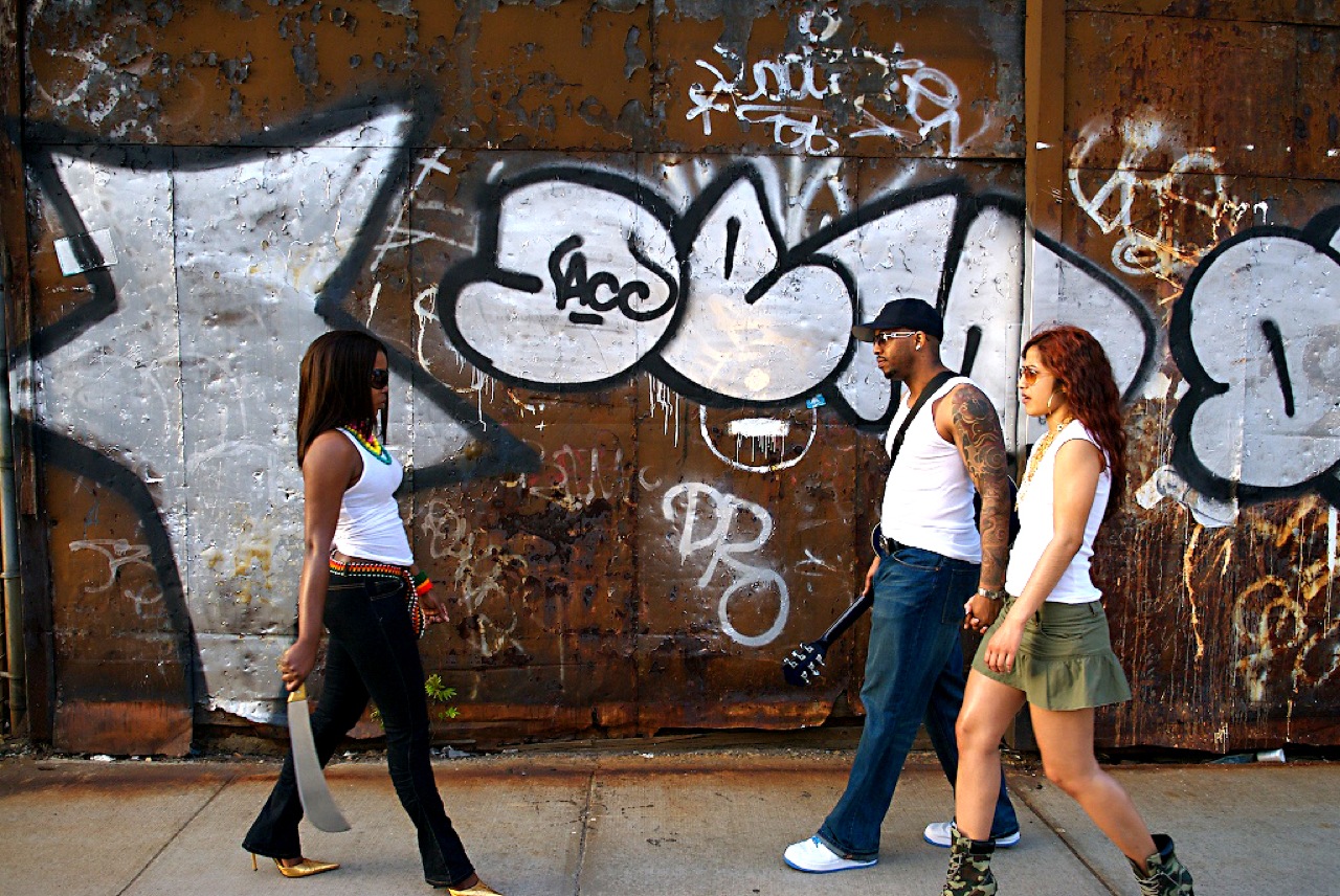 young people walking down the sidewalk by graffiti on a wall