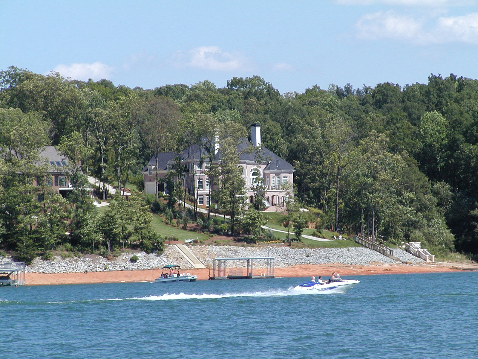 a house and a boat are on the water near the shore