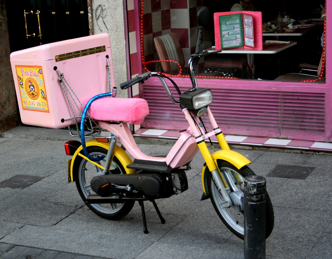 a yellow moped is parked outside a storefront