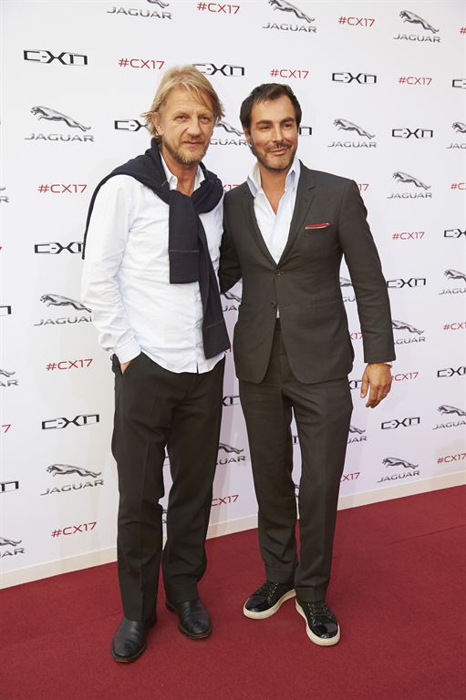 two men standing on top of a red carpet