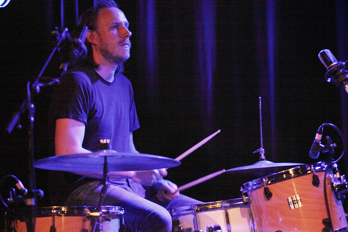 a man sitting at a drum kit on stage