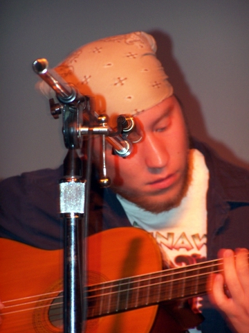 a man wearing a hat playing an acoustic guitar