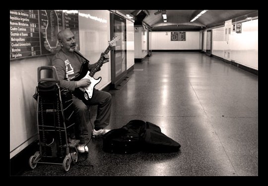 man sitting on the floor next to luggage and guitar