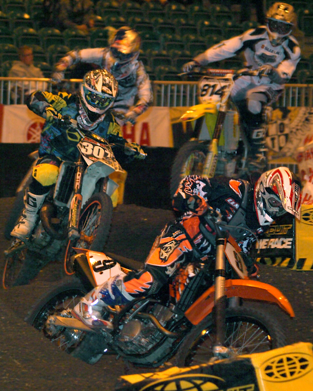 two people racing on dirt bikes in a dirt track