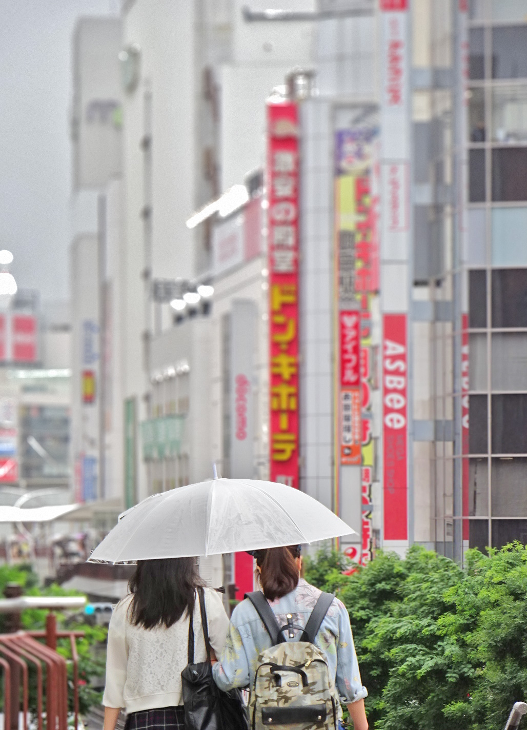 two people with backpacks are walking under an umbrella